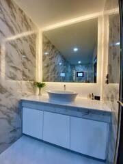 Modern bathroom with marble wall and illuminated mirror