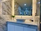 Modern bathroom with marble wall and illuminated mirror