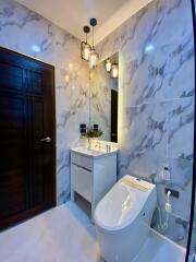 Modern bathroom with marble tiles, stylish lighting, and a bidet