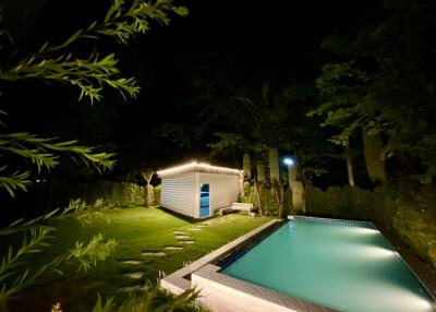 Night view of the backyard with a pool and a shed