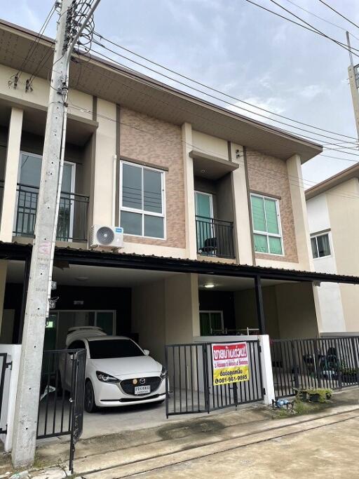 Front view of a modern townhouse with carport and balconies