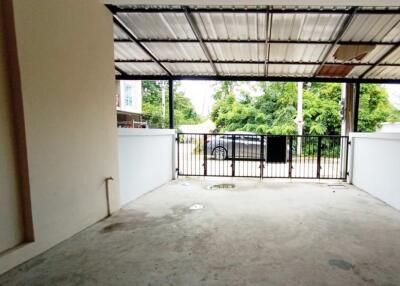 Open garage space with a metal roof and front gate