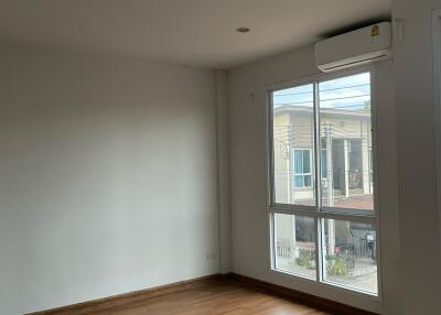 Spacious bedroom with wooden flooring and large window