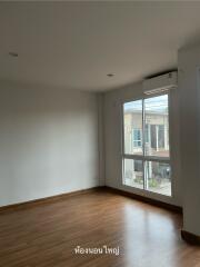 Spacious bedroom with wooden flooring and large window