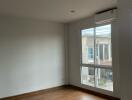 Spacious bedroom with wooden flooring and large window