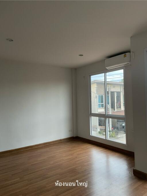 Spacious bedroom with wooden flooring and large window