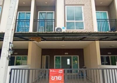 Exterior view of a multi-floor townhouse with a front gate.