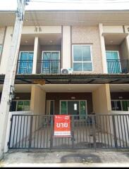 Exterior view of a multi-floor townhouse with a front gate.