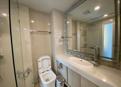 Modern bathroom with glass shower, sink, and toilet