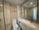 Modern bathroom with glass shower, sink, and toilet