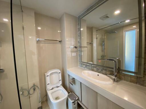 Modern bathroom with glass shower, sink, and toilet