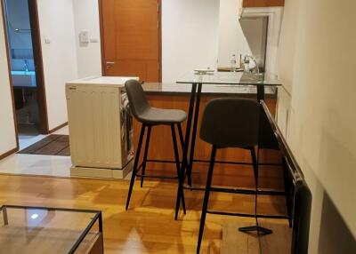 Modern kitchen and living area with wooden flooring and breakfast bar