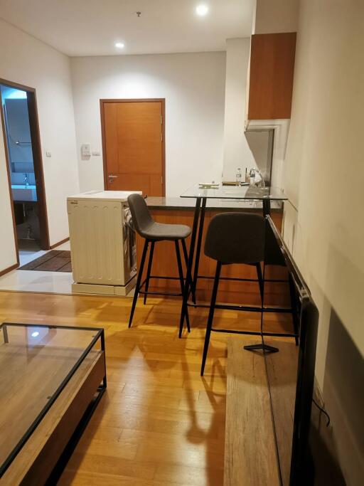 Modern kitchen and living area with wooden flooring and breakfast bar