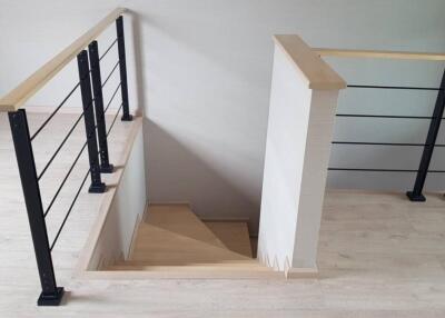 Modern staircase with wooden steps and metal railing leading downstairs