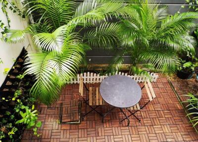 Outdoor patio with round table, chairs, and lush greenery