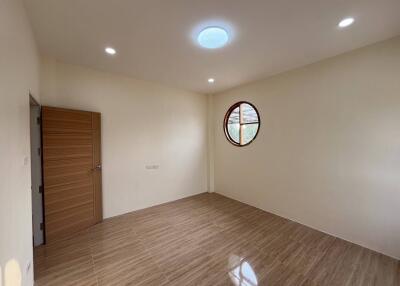 Spacious empty bedroom with wooden flooring and round window