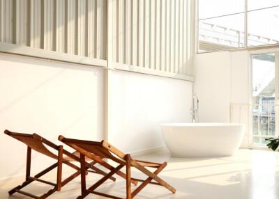 Modern bathroom with large windows, standalone tub, and wooden chairs