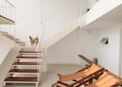 Modern duplex living area with wooden deck chairs and a staircase