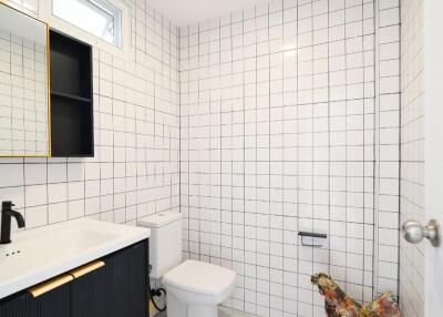 Modern bathroom with black vanity, white square tiles, toilet, and unique decorative chicken