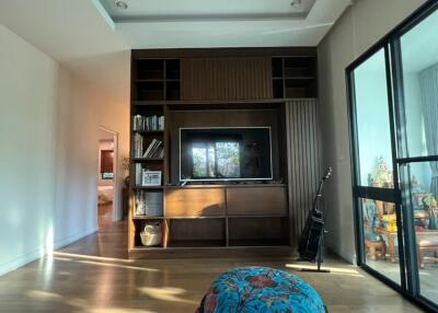 Living room with a TV stand, bookshelves, and a glass door leading to another room