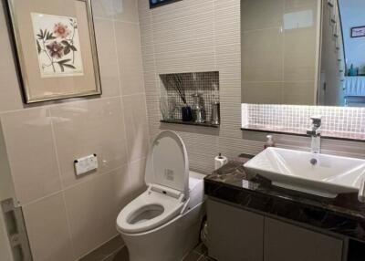 Modern bathroom with toilet, sink, and wall-mounted artwork