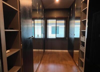 Spacious walk-in closet with wooden flooring and ample storage space