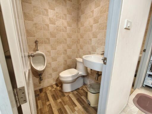 A small bathroom with toilet, sink, and urinal