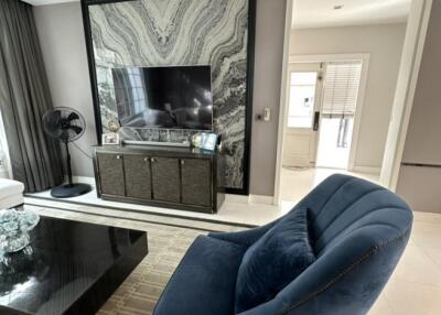 Modern living room with blue armchair, TV, and large window