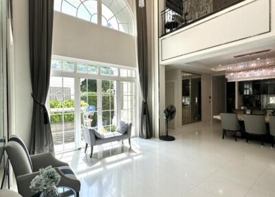 Modern living room with high ceiling, chandelier, and large windows