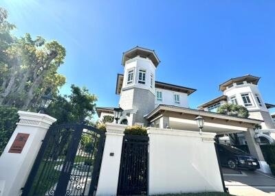 Exterior view of a large residential building with gates and a carport