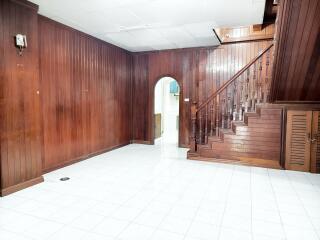 Wood-paneled living room with arched doorway and stairs