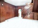 Wood-paneled living room with arched doorway and stairs