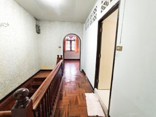 Well-lit hallway with wooden flooring and windowed door