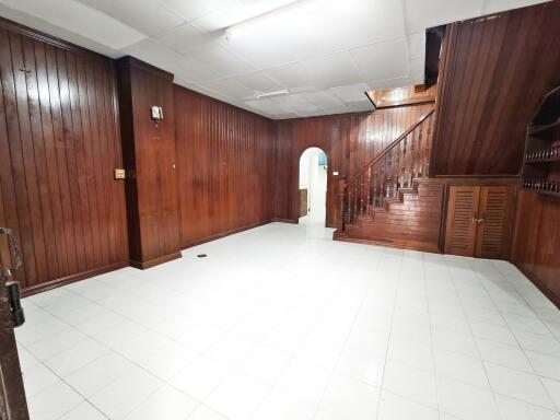 Spacious wooden-paneled living room with staircase