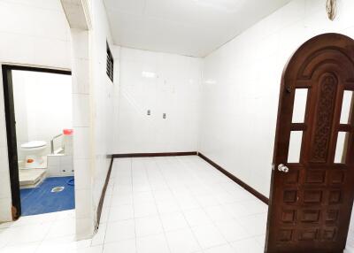 Empty room with a carved wooden door and adjacent bathroom