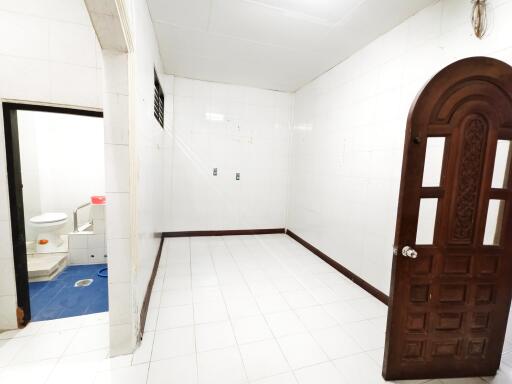 Empty room with a carved wooden door and adjacent bathroom