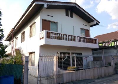 Exterior view of a double-story house with a balcony and a gated front yard.