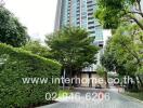 Vertical view of a modern high-rise building with landscaped pathway and greenery.