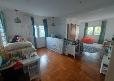 Spacious bedroom with wooden flooring and natural light