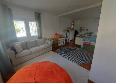 Open living space with sofa, large rug, children