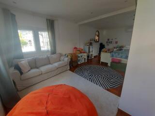 Open living space with sofa, large rug, children