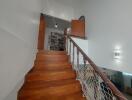 Interior wooden staircase with net railing leading to upper floor with view of bookshelves