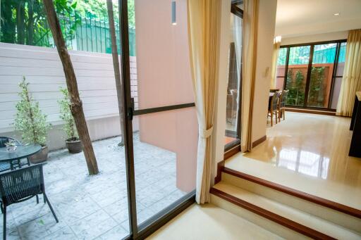 Living area with outdoor patio, featuring sliding glass door, trees, and dining area