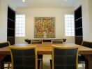 Dining room with wooden table, black chairs, and colorful wall art