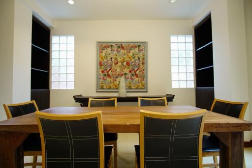 Dining room with wooden table, black chairs, and colorful wall art