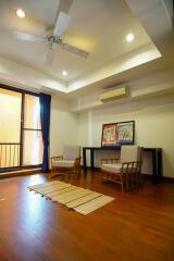 Living room with wooden flooring, chairs, a rug, and a ceiling fan