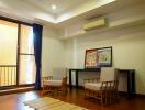 Living room with wooden flooring, chairs, a rug, and a ceiling fan