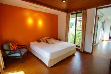 Spacious bedroom with a large bed and an orange accent wall