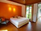 Spacious bedroom with a large bed and an orange accent wall