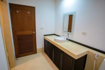 Bathroom with a wooden door and a sink with a mirror